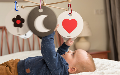 Baby schaut sich fokussiert Kontrastkarten auf einem Mobile an