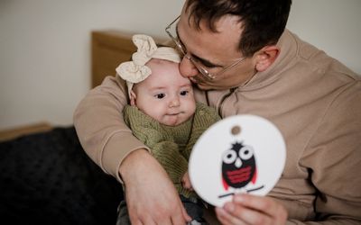 Papa und Baby kuscheln und betrachten gemeinsam eine Kontrastkarten