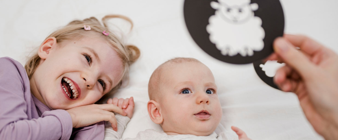 Kind und Baby schauen sich eine Kontrastkarten an